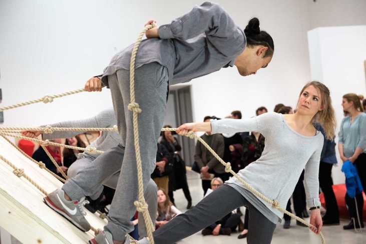 Two dancers performing Simone Forti's Slant Board