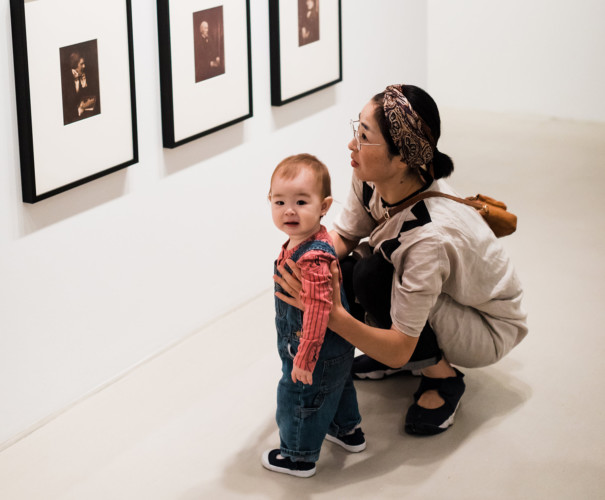 Woman and small child in front of photographs.