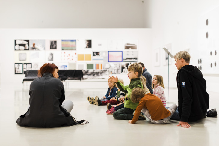 Konstpedagog i utställnginsrum med en grupp barn.