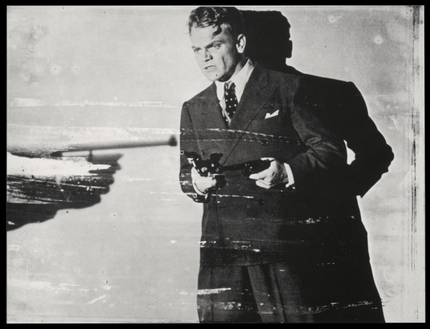 Man i kostym med pistol i handen.