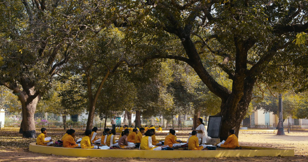 Videostill with youngsters sitting under grove.