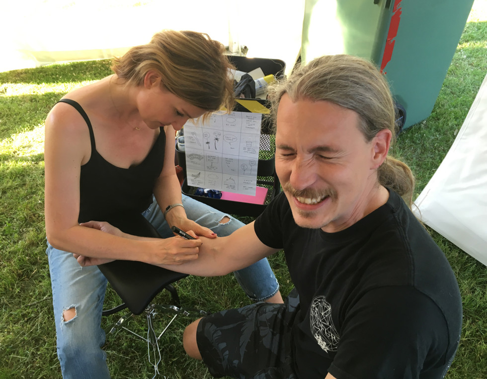 Man getting tatoo from woman.