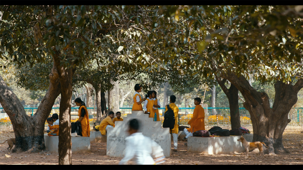 Still from video with youngsters gathering under grove.