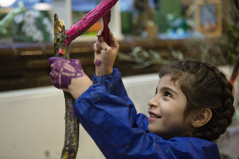 Young girl painting a stick in Verkstan.