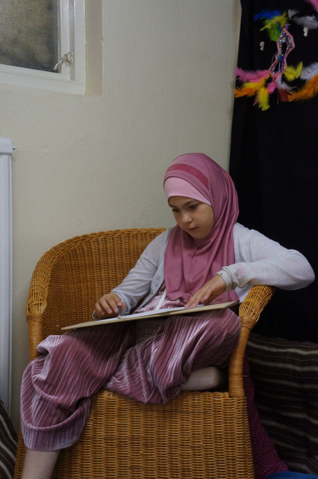 Girl sitting in chair drawing.