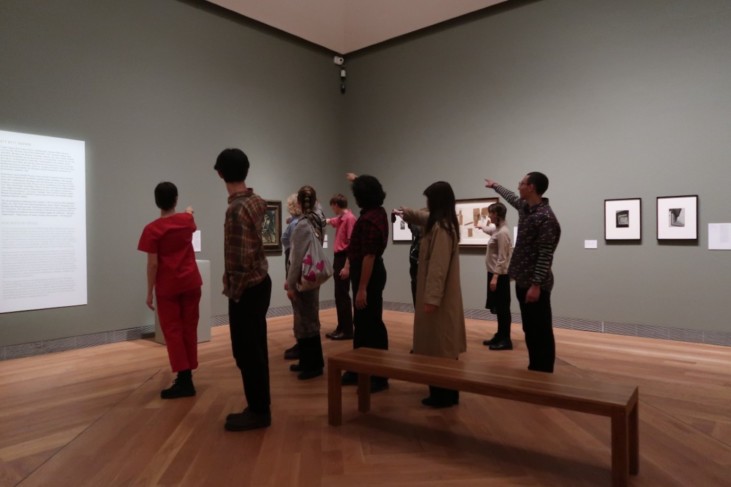 People standing in exhibition room pointing fingers