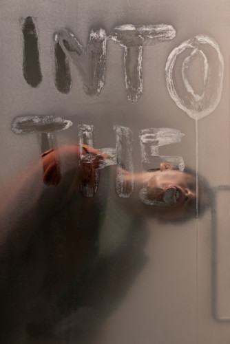 Person acting in performance behind a glass wall