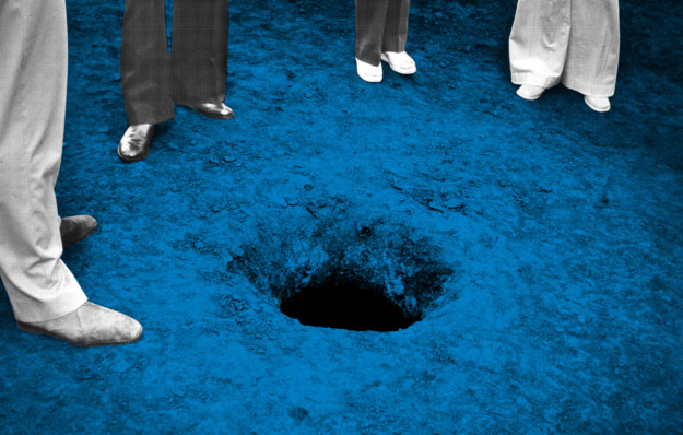 Photo of hole in ground and feet of four persons standing around it
