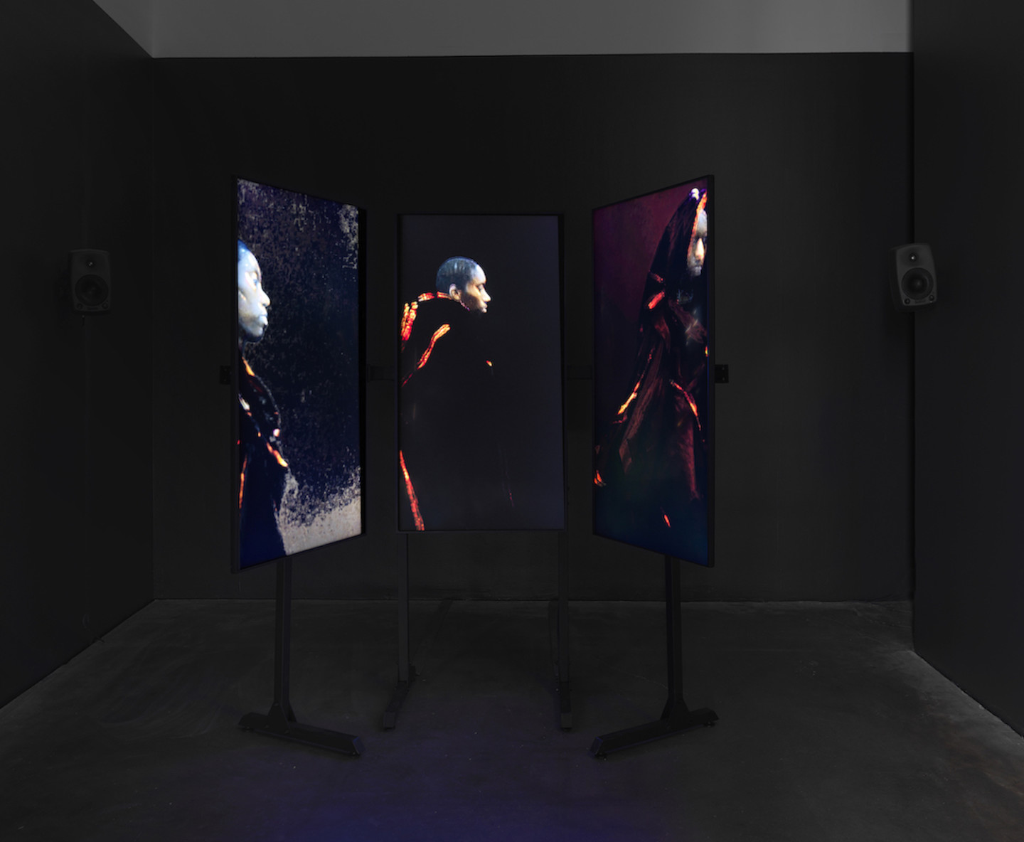 Photo of three video screens with dark figures