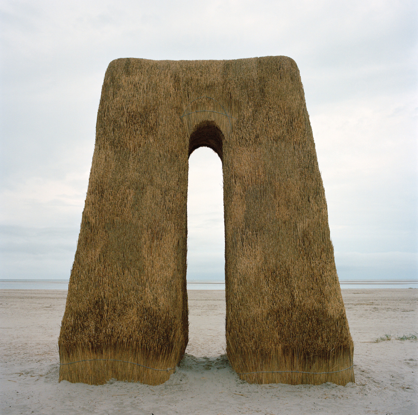 Foto av skulptur gjord i halm på strand