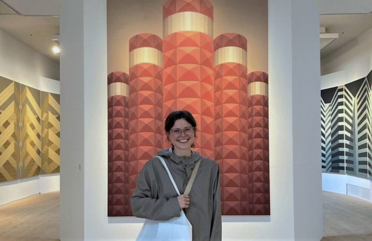 foto av leende kvinna som står framför stora målningar