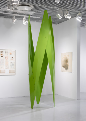 foto av utställningsrum med grön skulptur och målningar i bakgrunden