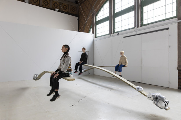 three persons sitting on planks