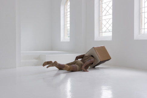 photo person on floor in white room with box on head