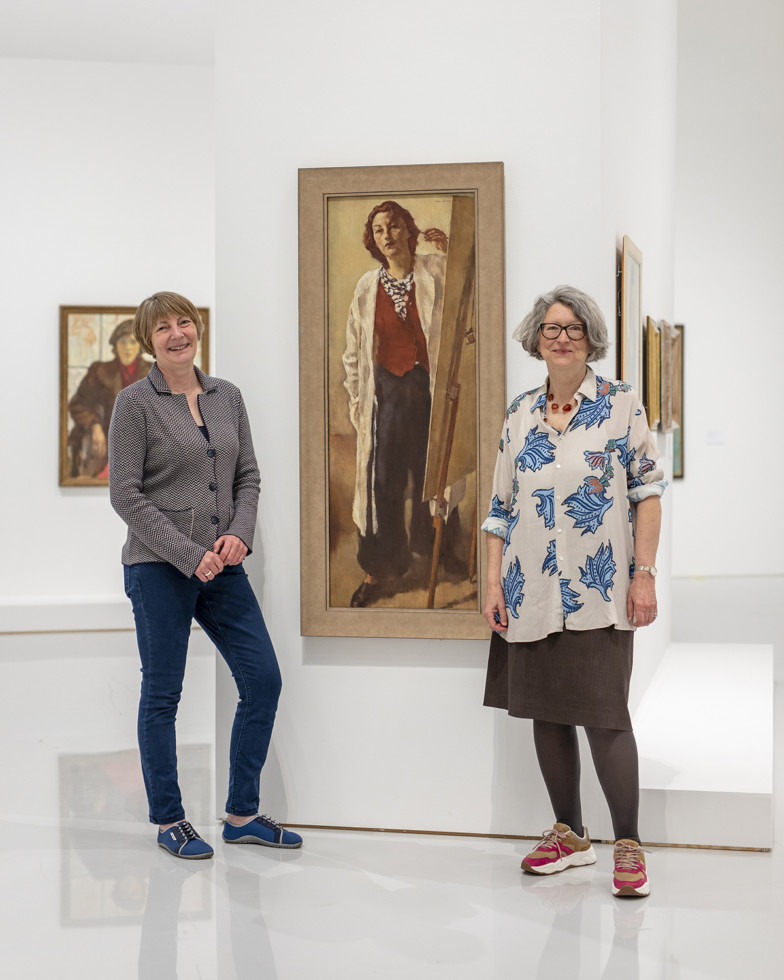 two women in front of painting