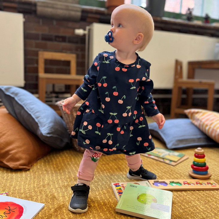 babygirl standing with toys around her