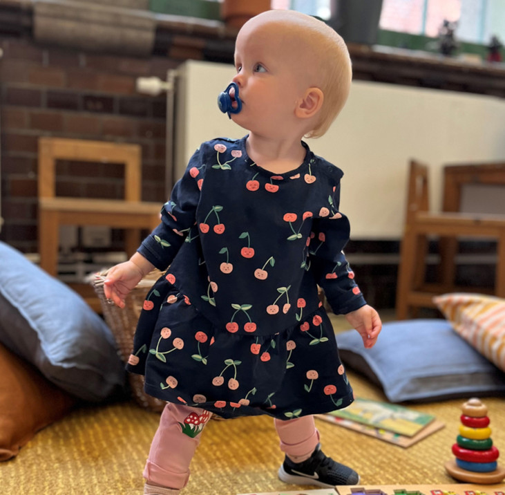 babygirl standing with toys around her