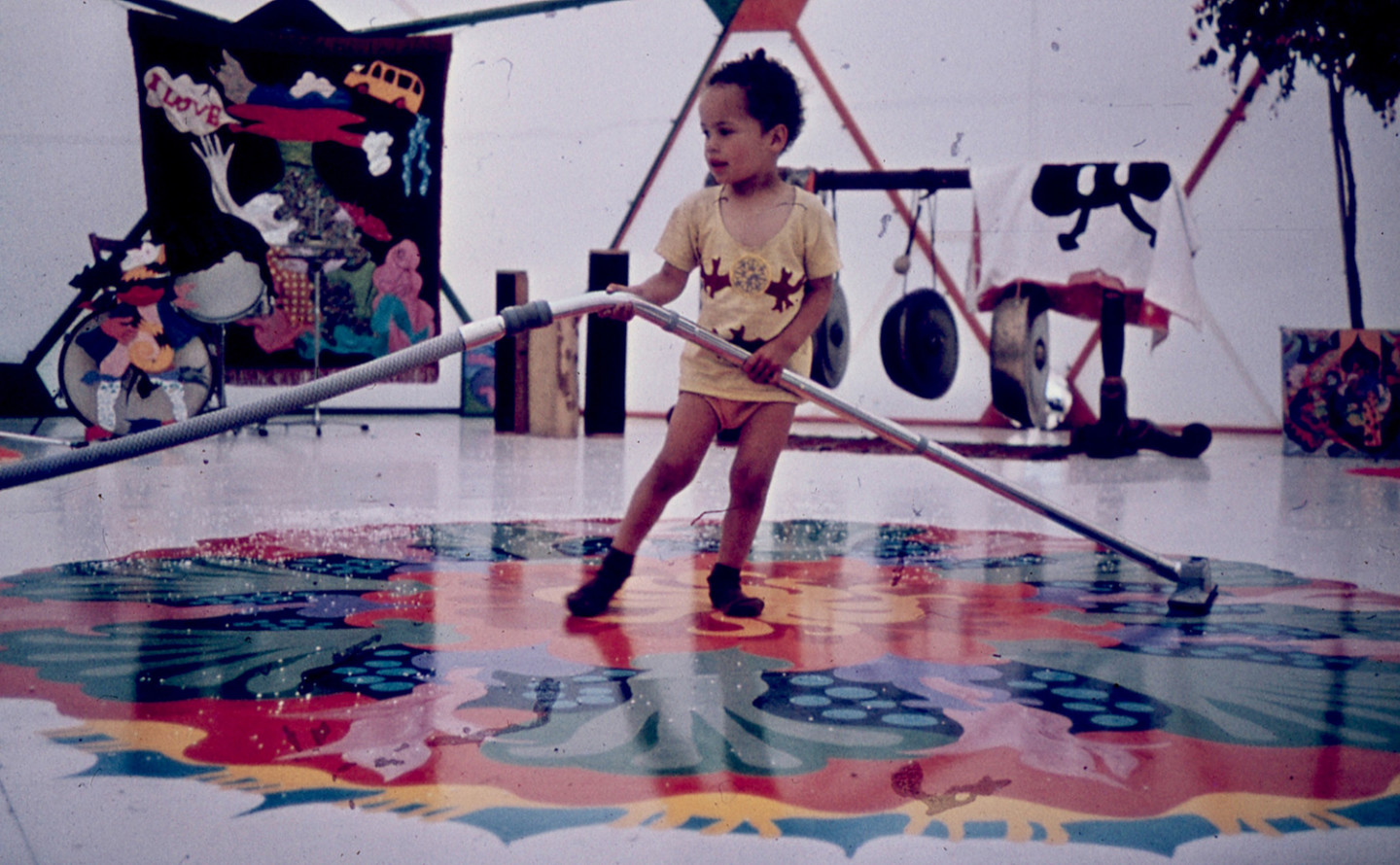 child holding long hose on floor with painted pattern