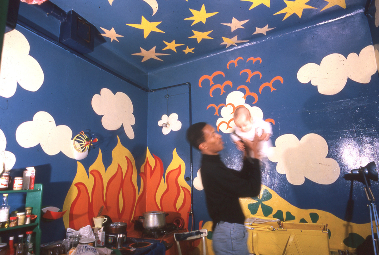 man holding baby in room with walls painted in strong colors