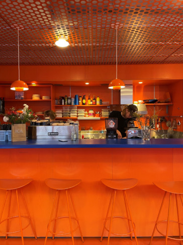 man behind orange and blue bar desk