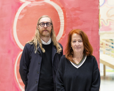 photo of man and woman in front of painting