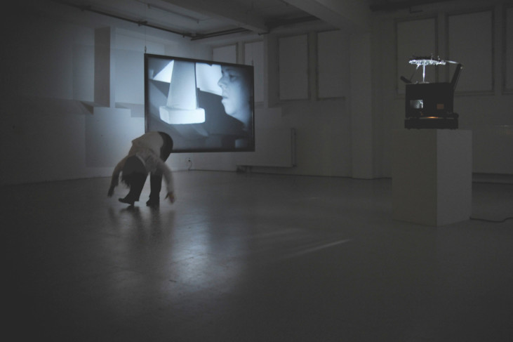 person som böjer sig fram i rum med videoprojektion i bakgrunden