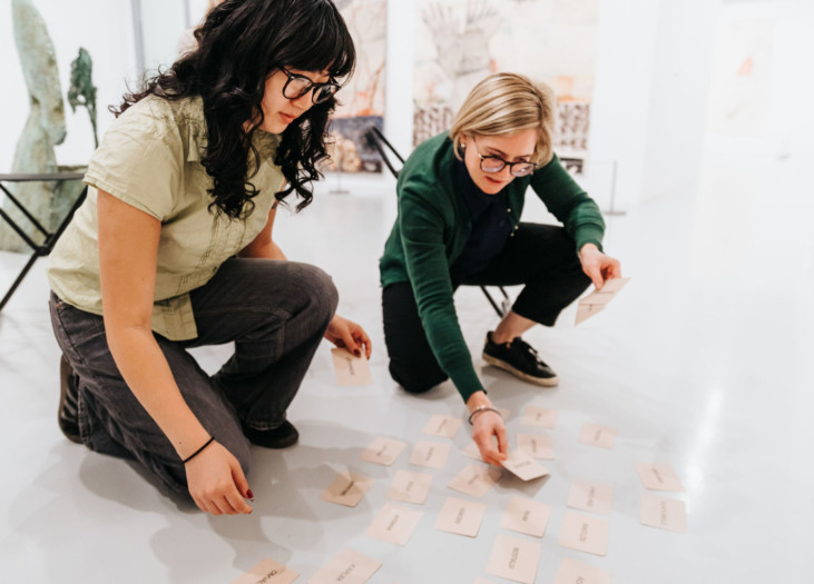 två personer plockar upp kort från golvet