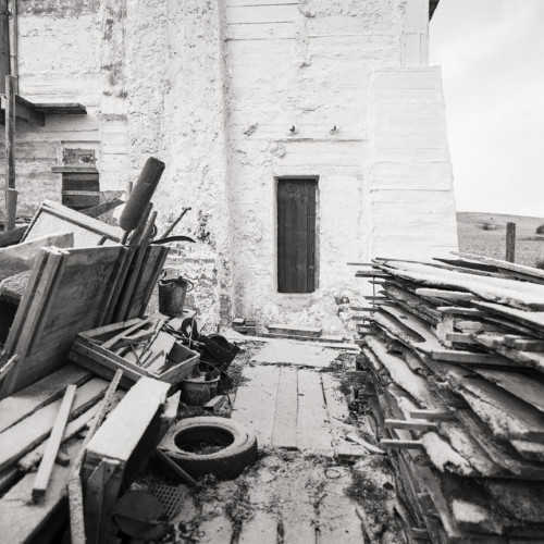 A photograph of piles of wood in front of a building