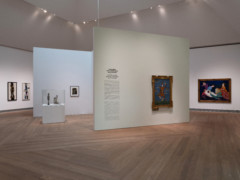 Installation of view Pink Sails. Photo of a white hall with wooden floors, on the walls hangs artworks and two sculptures are placed to the left in the image.