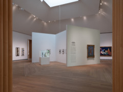 Installation of view Pink Sails. Photo of a white hall with wooden floors, on the walls hangs artworks and two sculptures are placed to the left in the image.