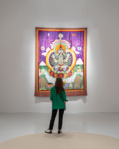 person står framför stort textilt konstverk