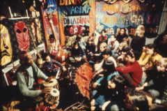 photo with lots of people sitting on floor surrounded by tapestries