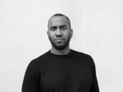 The artist Rashid Johnson stands in front of a plastered facade