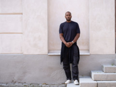 The artist Rashid Johnson stands in front of a plastered facade