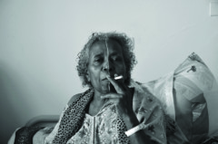 black and white photo of smoking woman with white line painted in face