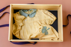 An image of a child's dress in a wooden box