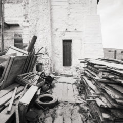 Photo of piles of wood in front of buildingiles of wo