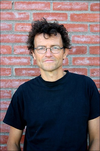Portrait photo of Lars Tunbjörk in front of a brick wall.