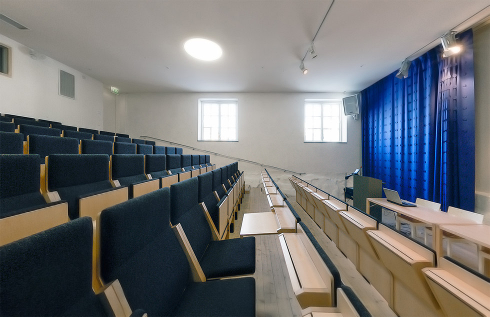 Rows of chairs in front of stage with blue curtain.