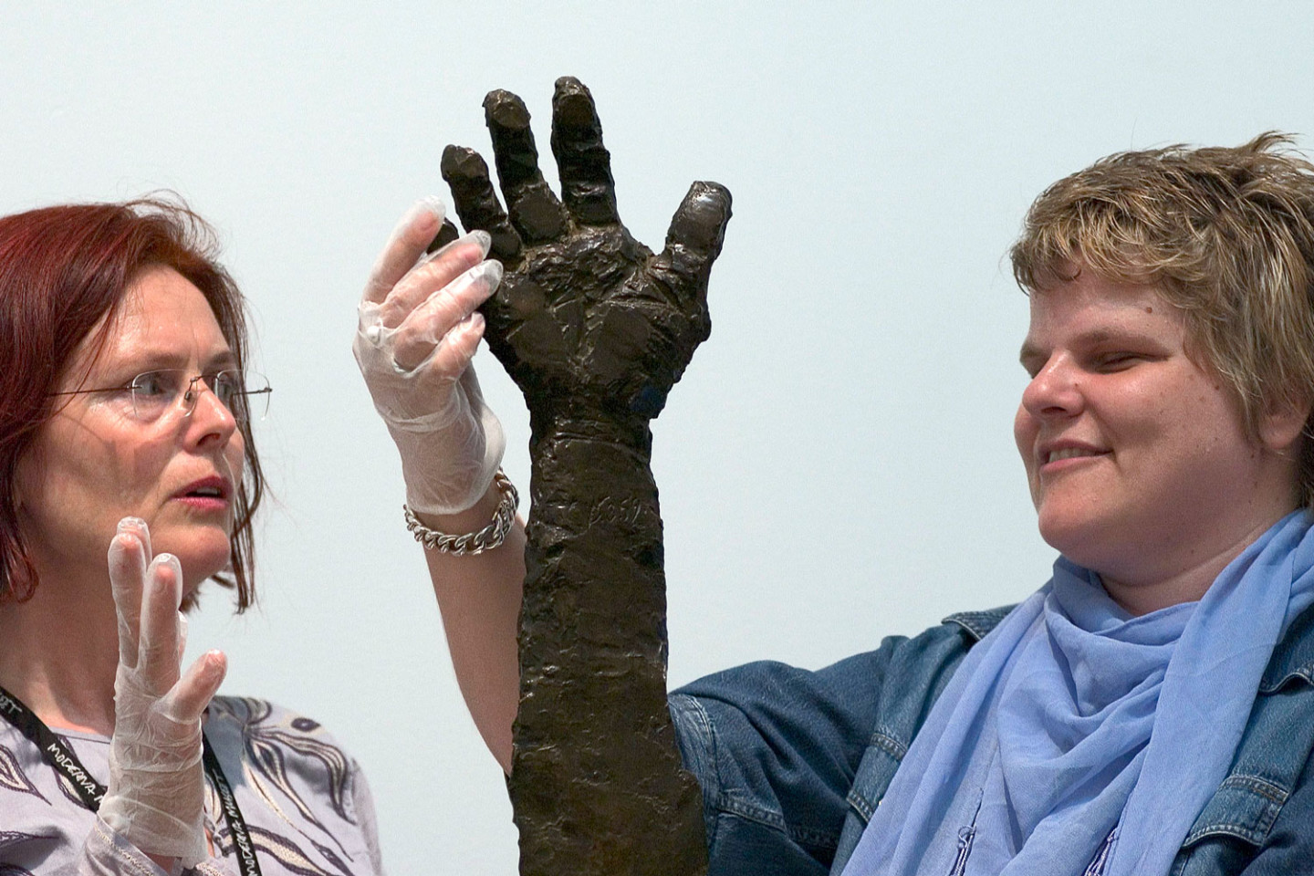 Person touching a sculpture. Art educator standing beside.
