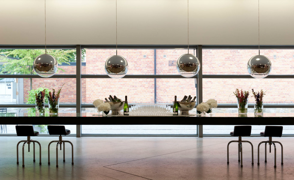 Long table set with champagne and glasses in front of large windows.