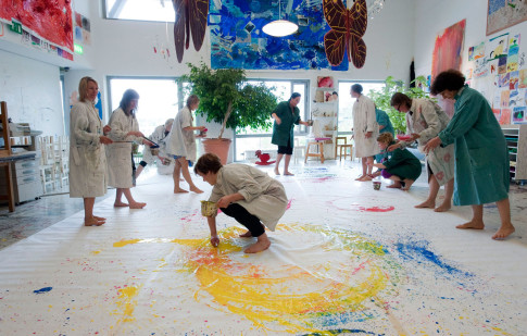 Grupp vuxna som arbetar med färg på stora papper på golvet i Verkstan.