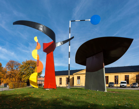 Colorful sculpture outdoors on green grass under blue sky.