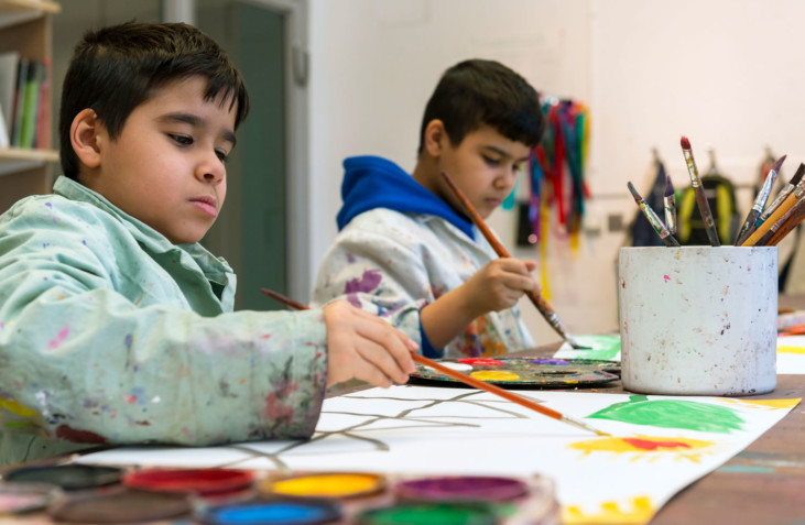 Två barn målar i med penslar och färg i Verkstan.