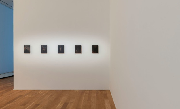 Black, square shaped artworks on white wall.