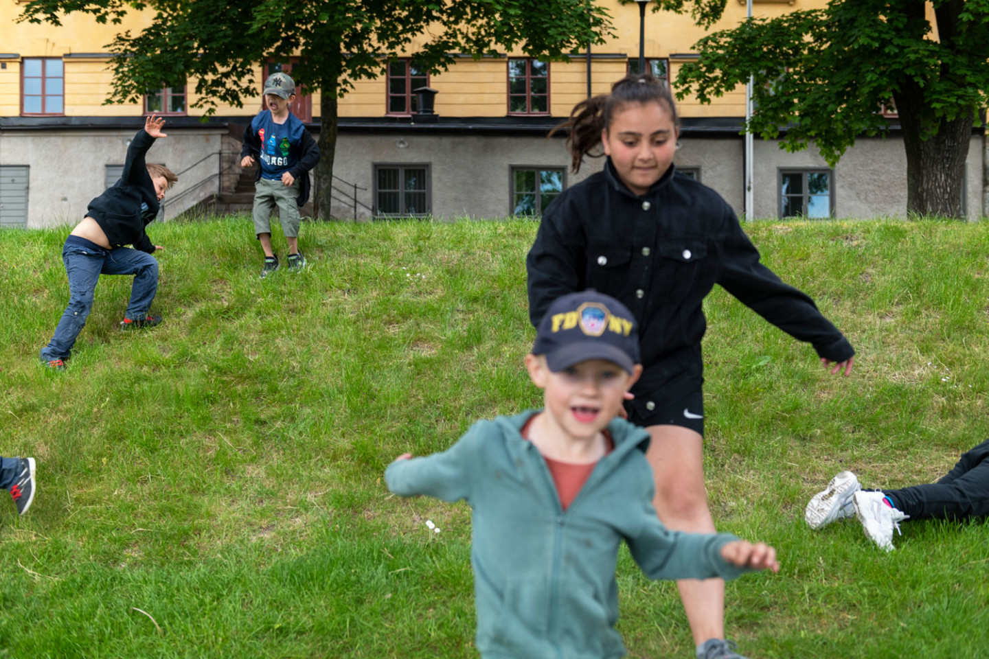 Barn springer på gräsbevuxen kulle.