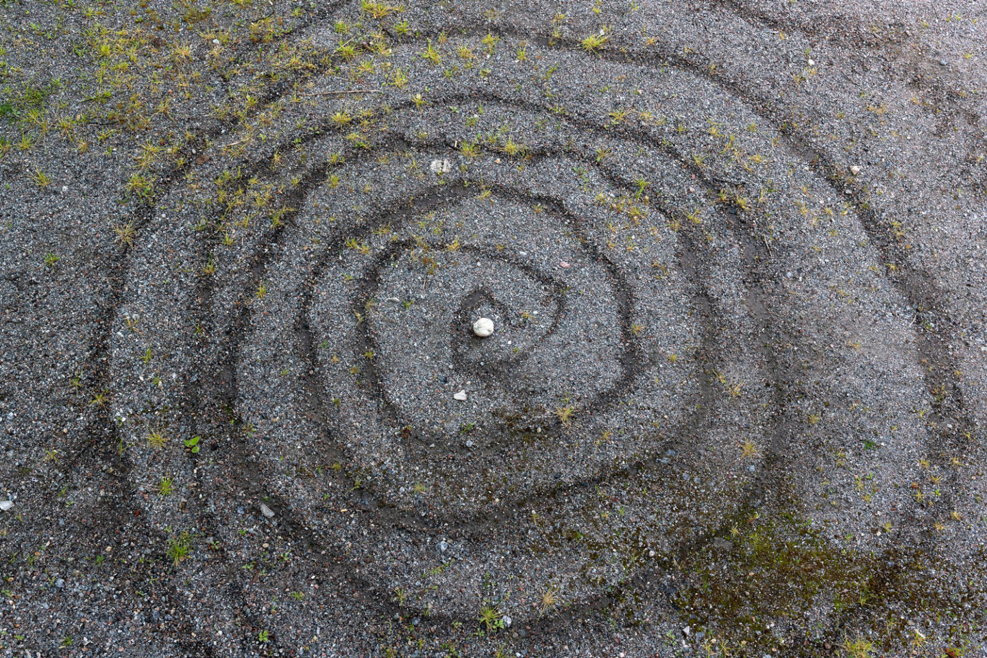 Spiral i vatten på grus med en vit sten i mitten.