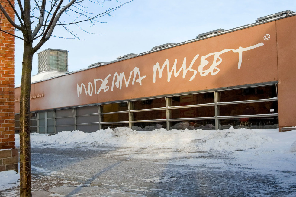Museibyggnaden med Moderna Museets logga i vinterlandskap.