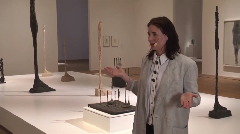 Person stands in front of podium with sculptures.