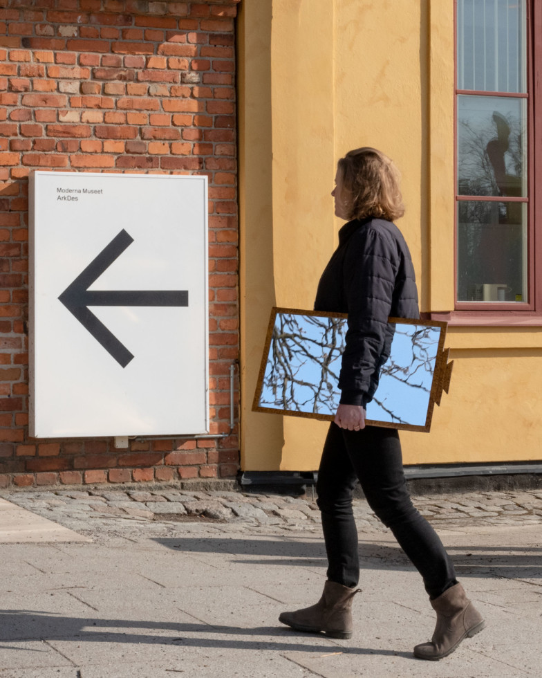 En person som går med en spegel under armen utanför museet